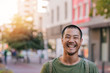 Young Asian man standing on a city street laughing