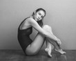 © fStop - Portrait of beautiful fashion model wearing leotard while sitting on hardwood floor against wall