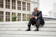 © Inti St Clair/Blend Images - Black businessman sitting on staircase texting on cell phone outdoors