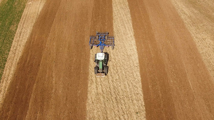 Wall Mural - 
aerial view of a tractor at work on agricultural fields -  tractor cultivating a field in spring