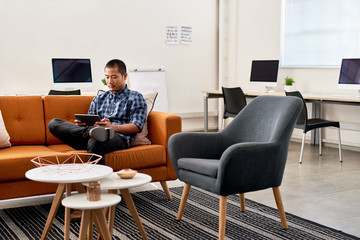 Focused Asian designer working on a tablet in an office