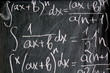 Abstract background of chalk written math formulas on black board