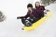 © Mike Kemp/Blend Images - Smiling girls sliding in toboggan on hill in winter