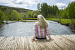 © Steve Smith/Blend Images - Caucasian woman sitting on dock at river