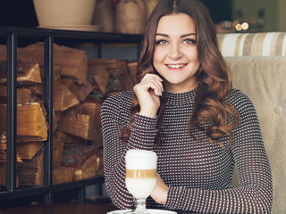 Wall Mural - Beautiful young woman sitting in italian style cafe with cup of latte, creative toning