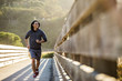 © Adam Hester/Blend Images - Smiling Mixed Race man running on footbridge