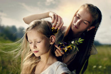 Girl Placing Flower In Sister's Hair