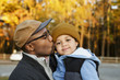 © Roberto Westbrook/Blend Images - Father kissing son on cheek in park