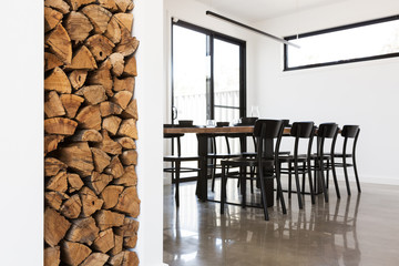 Wood stack feature in lounge with dining table in background