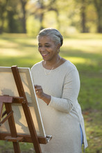 Black Woman Painting On Canvas In Park
