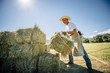 © Inti St Clair/Blend Images - Caucasian farmer lifting bale of hay