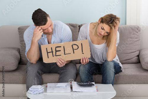Fotomural Worried Couple Holding Help Sign While Calculating Bills