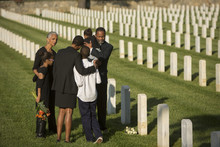 Multi-generation Black Family Hugging In Military Cemetery