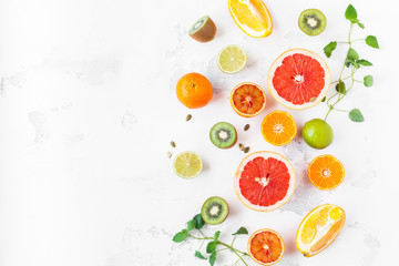 Fruit background. Colorful fresh fruit on white table. Orange, tangerine, lime, kiwi, grapefruit. Flat lay, top view, copy space