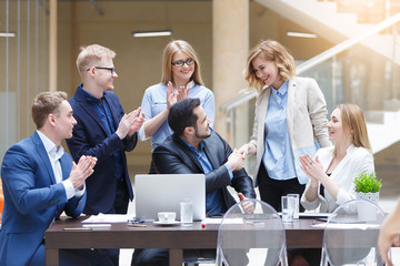 happy business team enjoy good news together in modern office with laptop