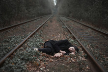 Caucasian Woman Laying Between Railroad Tracks