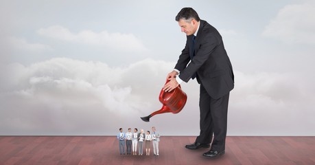 Wall Mural - Large businessman watering employees against sky