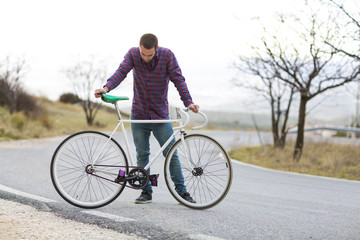 Cyclist man riding fixed gear sport bike in sunny day on a mountain road