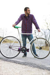 Cyclist man riding fixed gear sport bike in sunny day on a mountain road