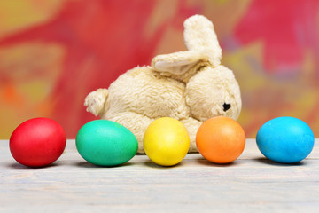 rabbit toy, painted easter eggs on colorful background