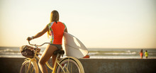 Caucasian Teenage Girl Carrying Surfboard On Bicycle