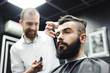 © nagaets - Master cuts hair and beard of men in the barbershop, hairdresser makes hairstyle for a young man