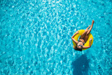 Fototapeta  - Beautiful woman enjoying the water in pool on inflatable
