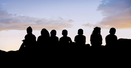 Canvas Print - Silhouette kids sitting on hill against sky