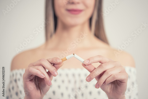 Cuadros en Lienzo happy young beautiful woman holding a broken cigarette,quit smoking concept