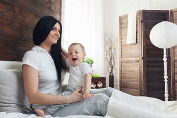 Wall Mural - Happy mother with her cute child on the bed having a good time