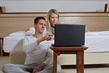 Couple using electronic devices, laptop computer. Family enjoying online shopping and lazy weekend at home