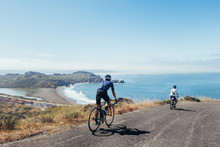 Group Of Cyclists, Teammates, Friends, Descending Windy Narrow Road Next To The Bay With Fog And Water And Blue Skys San Francisco In Norhtern California.