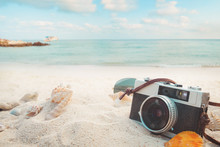 The Concept Of Leisure Travel In The Summer On A Tropical Beach Seaside. Retro Camera On The Sandbar With Starfish, Shells, Coral On Sandbar And Blur Sea Background.  Vintage Color Tone Styles.