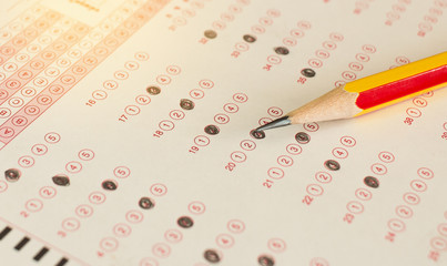 Wall Mural - standardized test exams form with answers bubbled in and color pencil resting on the paper test, edu