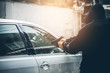 A robber dressed in black pointing a gun at a driver in a car. Car thief concept.