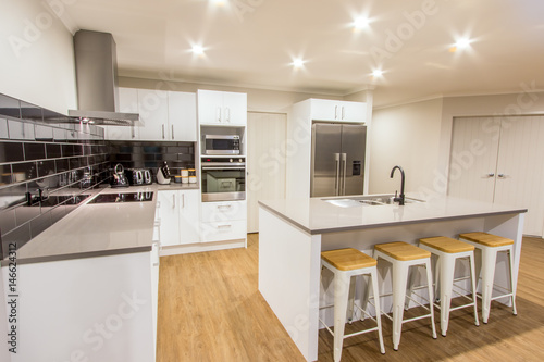 A Stunning White Modern Kitchen With Stone Bench Tops Tiled Black