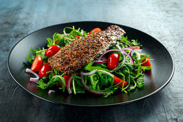 Smoked Mackerel Salad with tomato, chopped red onion, Ruccola on black plate.