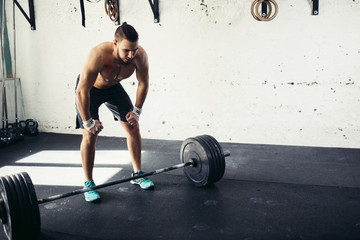 Exhausted athlete resting after heavy barbells training