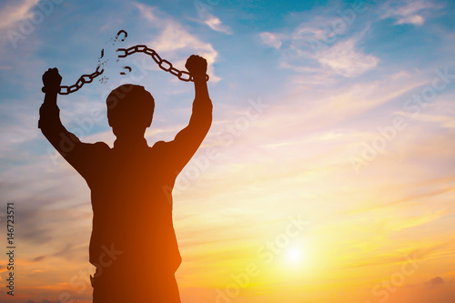 Fotografía Silhouette image of a businessman with broken chains in sunset