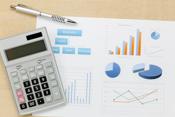 Top view business summary of the year and pen, chart calculator on wood  office desk background.