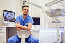Male Dentist In A Room With Medical Equipment On Background.