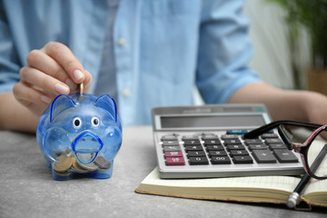 Wall Mural - Young woman putting money into piggy bank, closeup