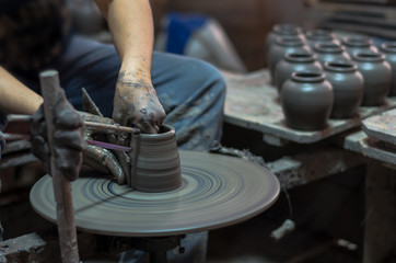 closeup hands of a potter, creating an earthen jar on the traditional machine, low light