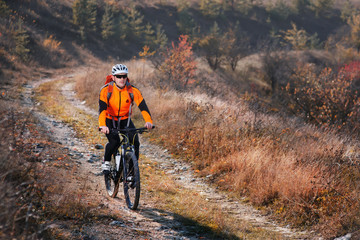 Portrait of young cyclist riding bicycle along trail in the countryside.