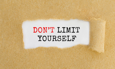 Poster - text don't limit yourself appearing behind ripped brown paper.