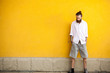 © DC Studio - Cool tattooed bearded hipster on yellow wall posing outdoor