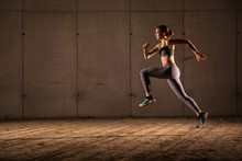 Young Woman Runner Is Seen Running In An Abandoned Hall. Running Is A Good Exercise For Cardio Vascular System And General Health And Weight Control.