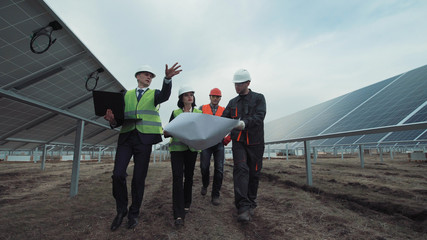 The engineers walking in the solar energy panels and discussing the blueprint.