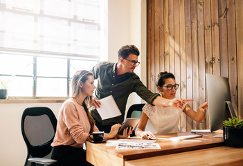 Wall Mural - Creative business team looking at a computer and discussing