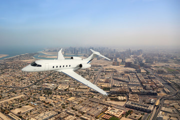 Wall Mural - Business jet airplane flying over city.